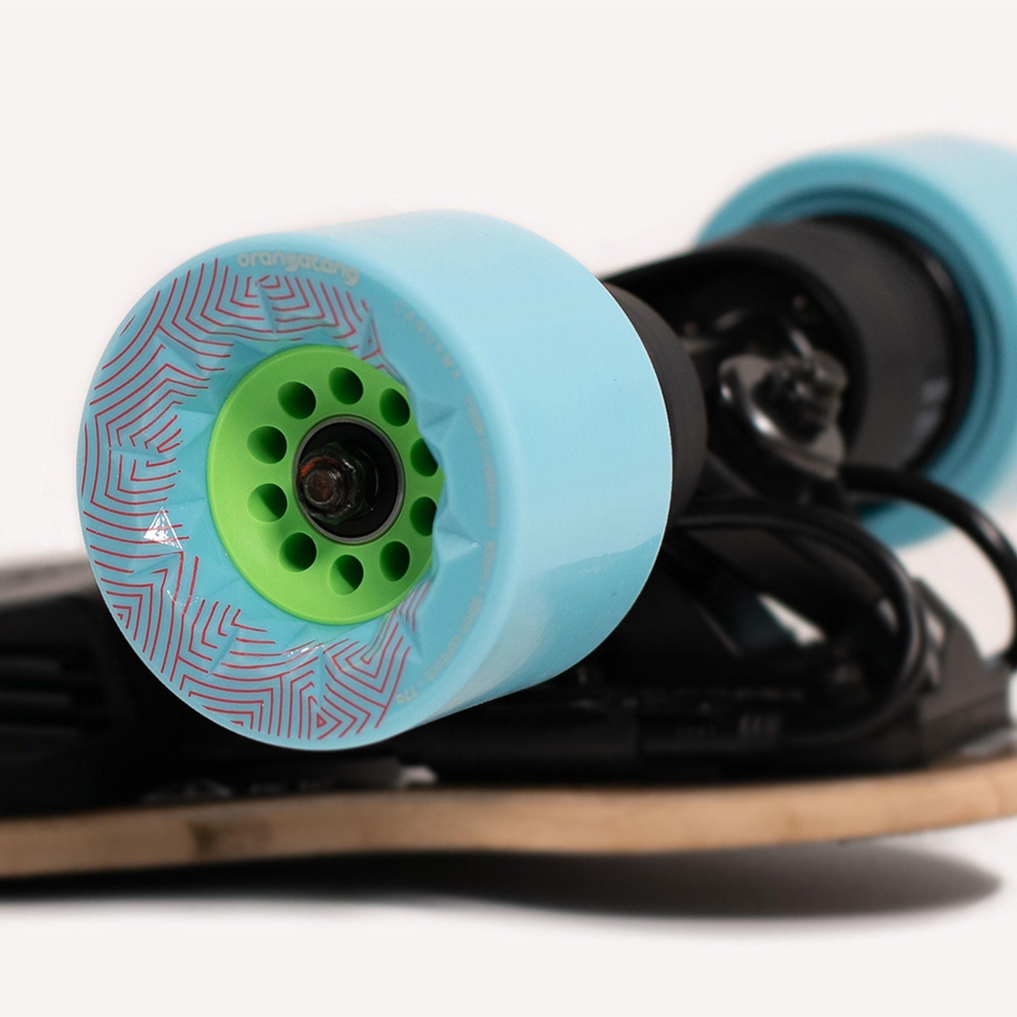 Light blue Orangatang Caguama 85mm wheel with green core mounted on an electric skateboard, white background