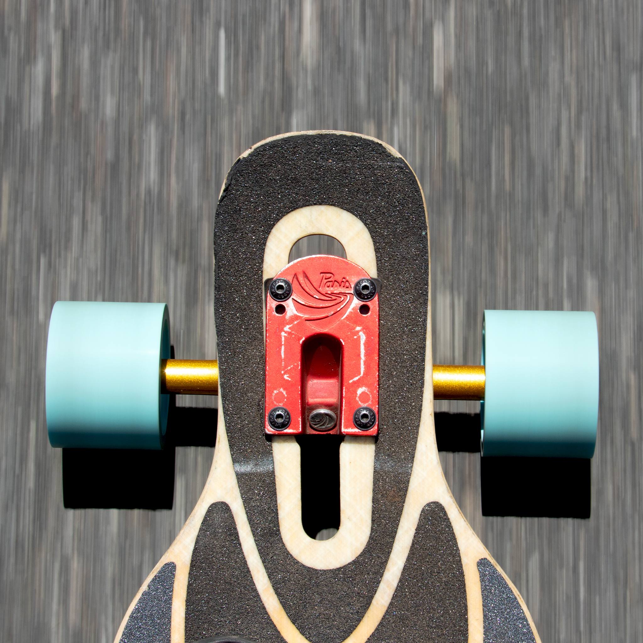 Overhead view of a longboard's truck with light blue Orangatang In Heat 75mm wheels rolling over asphalt