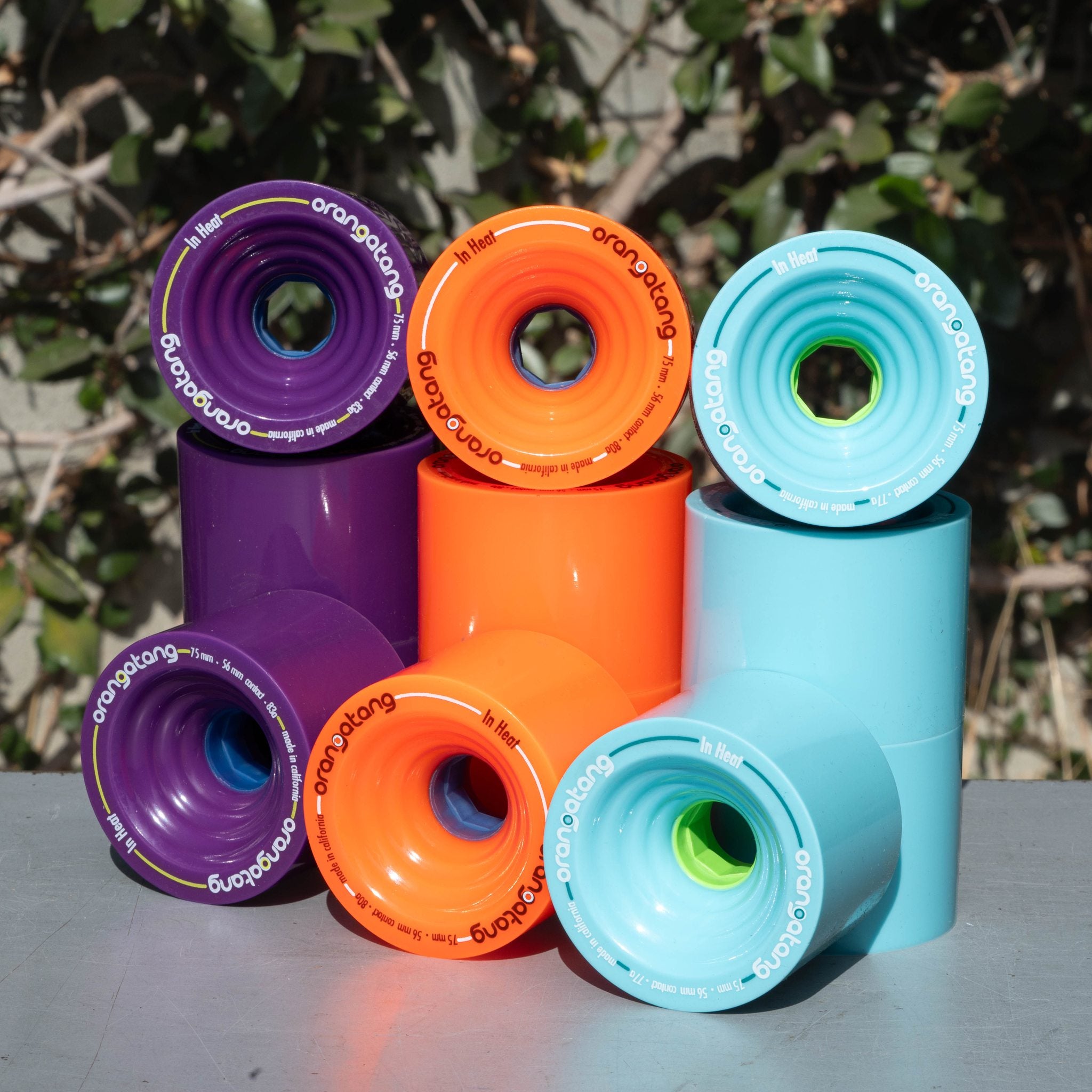 Stacked Orangatang In Heat 75mm wheels in purple, orange, and light blue, photographed outdoors